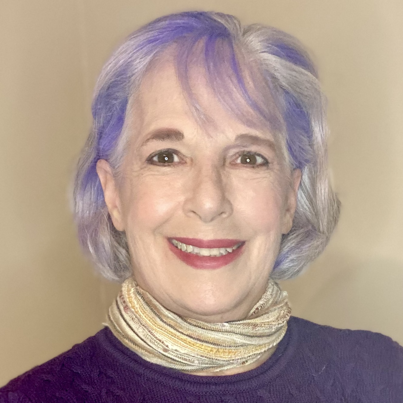 a smiling, middle-aged Caucasian woman with purple hair , a purple shirt, and red lipstick