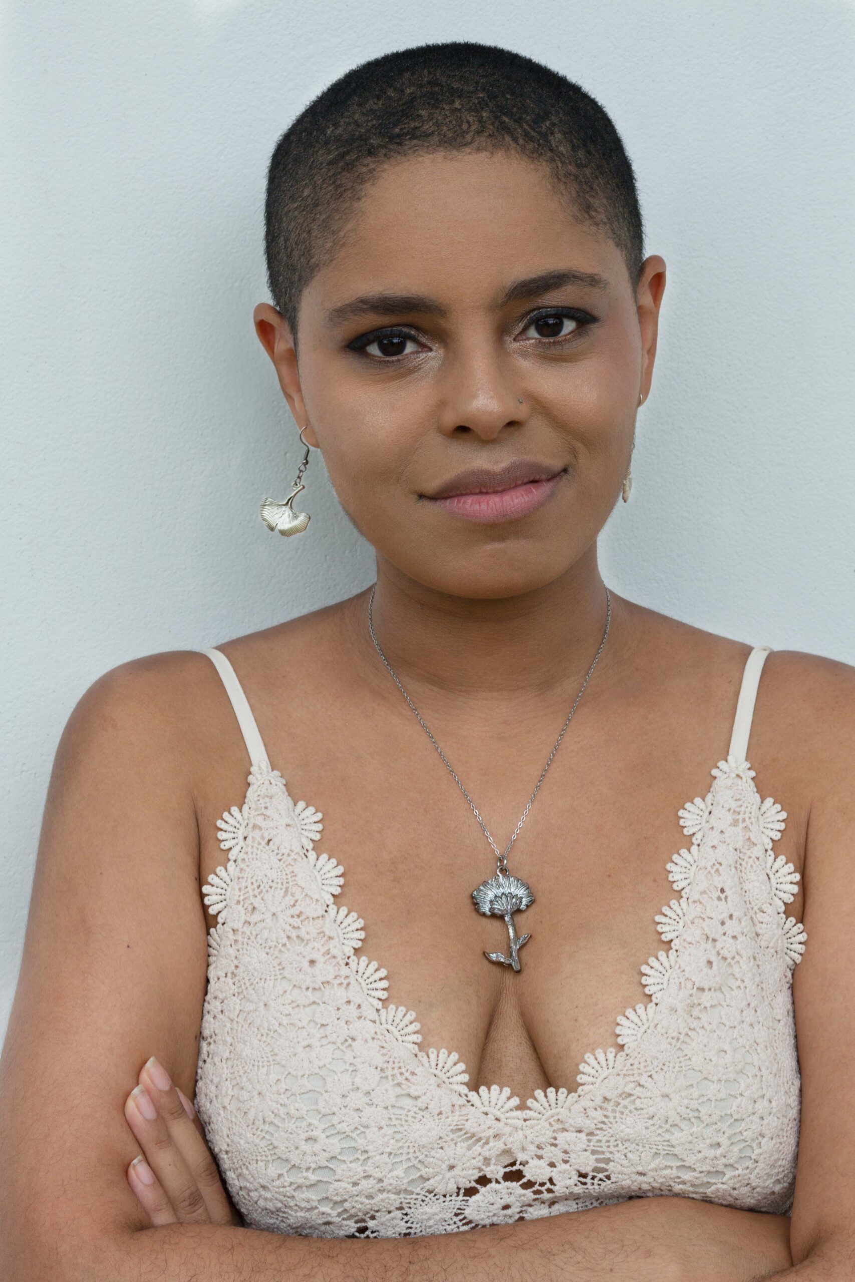 a smiling Black woman with short hair wearing a white tank-top